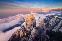 Mountain landscape at sunset. Amazing view from mountain peak on the high rocks, blue sky, clouds and sea in the evening. Low clouds. Colorful nature background. Adventure. Travel in Crimea. Cliffs