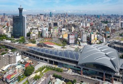 Aerial view over the modern & futuristic architecture of Taichung Train Station in downtown, with high rise towers standing among crowded buildings under blue sunny sky, in Taichung, Taiwan, Asia