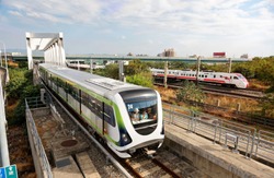 A metro train of Taichung MRT traveling thru a bridge near the High Speed Rail Station and a Puyuma Express train passing-by on the railway in the background, in Wuri District, Taichung City, Taiwan