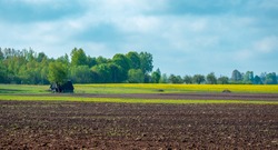 Plowed field in spring. An old house in the middle of the field.