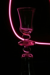 Glass cup with a neon pink speed line, describes a curve reflected in the object creating a beautiful design illustration with a black background.