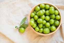 green plum wooden bowls on a light background. top view. spring fruit. healthy food