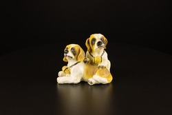 The statuette of two puppy dogs on a black background. Animal friends saint bernard with case a coin. Loyalty symbol concept. Close-up decor isolated.