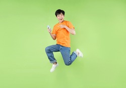 Asian man jumping and holding smartphone , isolated on green