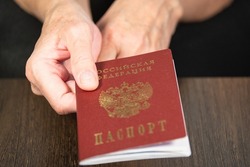 Passport in the hands of a woman. Text on the passport in Russian: Passport of the Russian Federation.