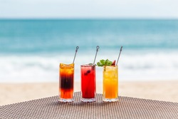 Bright Healthy Berries Cocktails on Table on Beach with Blue Sea on Background. Concept of Summer Vacations at Maldives or Caribbean Resorts. Fresh Fruit Ice Cold Drinks for Hot Weather Refreshment.