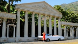 Rome Europe Italia travel summer vacation. Young romantic carefree woman tourist in red dress in European destination relax near vintage retro car with palms and ancient columns on background.