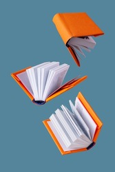 miniature books in an orange cover fly on a blue background