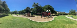 Panorama view urban playground at public park surrounded by large trees and skylines background in downtown Dallas, Texas, USA. Empty recreation place in hot summer day with sunny clear blue sky