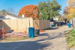 New fence installation with orange safety net at residential house near Dallas, Texas, America. Lumber board garden fence with colorful fall foliage at suburban back alley