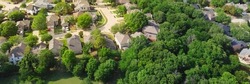 Panorama view an established neighborhood with matured trees and two story houses in Flower Mound, Texas. Upscale parkside Dallas suburbs single family homes large backyard lush green
