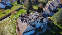 Aerial view upscale residential neighborhood with burnt house between other two story homes in Rochester, New York. Property totally damaged by fire disaster, insurance claim background