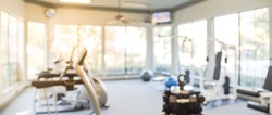 Blurred fitness center with cardio machines and weight, strength training equipment. Empty gym facility service room in apartment building complex at Houston, Texas, US. Panorama banner presentation.