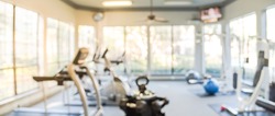 Blurred fitness center with cardio machines and weight, strength training equipment. Empty gym facility service room in apartment building complex at Houston, Texas, US. Panorama banner presentation.