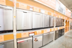 Blurred image row of compact fridges with reversible doors on display in home appliances selection of retail store. Stainless steel mini fridge, silverware storage for dorm rooms, man caves, home bars