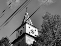 Baratia Church tower in Campulung Muscel, Arges Romania. Medieval Catholic church with monastery and bell tower with cross. Religion and Christianity. Black and white photography