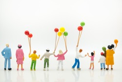 Miniature people: back view of happy family holding balloons with copy space using as background international family day, happy, love concept.