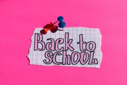 On a pink background, a paper with the inscription back to school is attached with a button.  card.  school background.