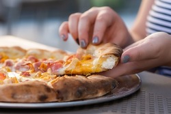 a slice of cheesy stuffed crust pizza in females hands. females hands taking a slice of stuffed crust pizza close-up. 