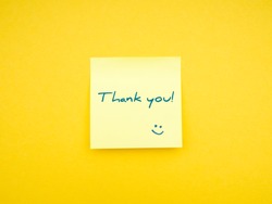 Yellow sticky note with caption Thank You! on vibrant yellow background. Studio shot photography