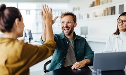 Successful business people giving each other a high five in a meeting. Two young business professionals celebrating teamwork in an office.