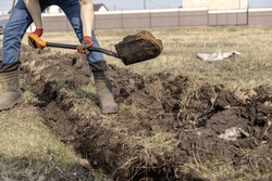 Drainage ditch. A man is digging a ditch. Laying a drainage pipe. Earthwork. A Worker digs soil with shovel.