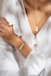 Woman hand posing showing her bracelet and pendant necklace. Women's hand with gold bracelet. Still life photo, minimalism