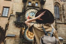 Blonde girl with hat and backback near famous clock in Prague, Czech Republic 