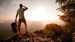 Hiker on top of the mountain enjoying sunrise over the tropical valley