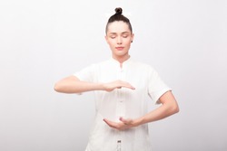fitness, sport, training and lifestyle concept - Young woman doing yoga exercise. Young Woman praticing tai chi chuan in the gym. Chinese management skill Qi's energy.
