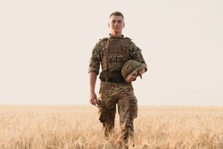 Soldier man standing against a field. Portrait of happy military soldier in boot camp. US Army soldier in the Mission. war and emotional concept.