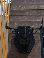 Head of a bull made of metal on the wooden background. Black iron sculpture of bulls head in Bukovel resort in Ukraine.