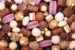 Assortment of chocolate colourful, festive sweets candy macaroons and nuts. Sweet candy background. mix of chocolate candies, top view. Choco lilac background.                            