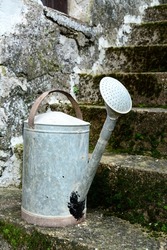 Vintage metal flower watering can on a stone staircase. 
