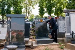 Mature man in black clothes on cemetery, holding a flower and mourning for family loss. Concept for Death, Mourning, Funeral and Spirituality.