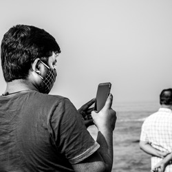 Man Holding mobile phone and clicking pictures and/or reading something