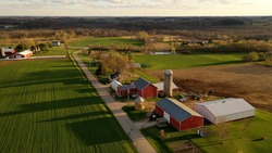 American midwestern countryside in springtime. Aerial view of farms with red barns in spring, rural road, agricultural fields
