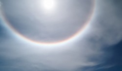 Solar phenomenon around halo the sun. Part bright spots of a solar halo colors rainbow white ring encircle near Center of Sun. Radiation aurora natural light displays in Sky. Soft blurry picture