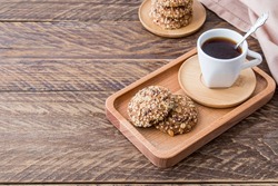 Diet biscuits made of oatmeal with sesame and flax seeds are served for breakfast on a wooden tray with freshly ground coffee
