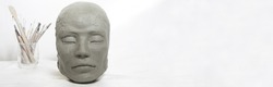 Isolated head sculpture and handmade art tools on white background. Portrait of a female mask for art instruction and workshops.