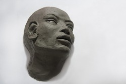 Clay sculpture and art tools. Female head and face on white background. Fine art studio.