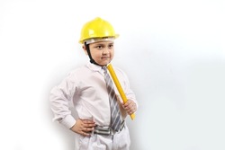 A kid wearing an engineer uniform portraying as a professional contractor. Holding a helmet in his hand acting like a builder and real estate engineer. The young boy is wearing a school uniform. 