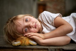 Portrait of unfortunate stray kid lying on the board in the dirty alley, shallow depth of field.