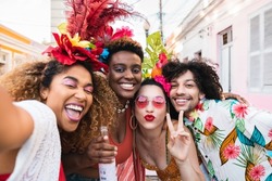 Friends in costumes have fun at carnival party in the street. Brazil holiday fun selfie with group of people together