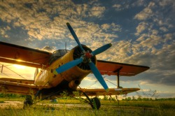 HDR foto of an old airplane on green grass and sunset background