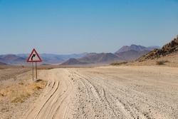 close up of a washboard gravel road and warning road sign in Namibia