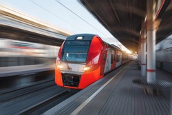Passenger high speed red train with motion blur in station platform with benches for people