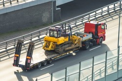 Bulldozer on a heavy platform for transportation. Long bed truck trailer for transporting heavy construction equipment