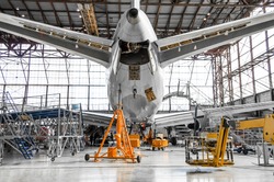 Large passenger aircraft on service in an aviation hangar rear view of the tail, on the auxiliary power unit