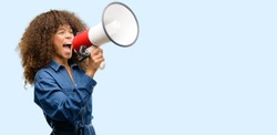 African american woman wearing blue jumpsuit communicates shouting loud holding a megaphone, expressing success and positive concept, idea for marketing or sales